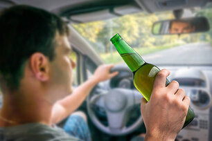 Young unfocused man drinking beer and driving car