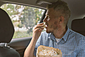 Man is eating popcorn inside of a car