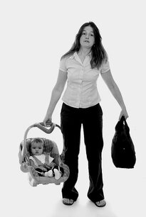 Mother carrying her young son to/from their car in the removable part of his carseat