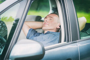 Man sleeping in the car before next part of the jurney