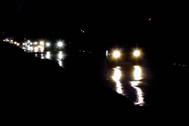 traces of car headlights at night reflected in wet rainy asphalt city roads