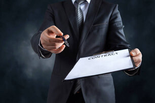 Businessmans hand holding a pen requesting a signature on a contract