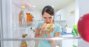 asian woman open refrigerator in kitchen and there has bad smell from salad