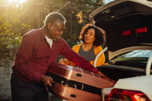 Happy family, african american man and woman, loading luggage into car for vacation
