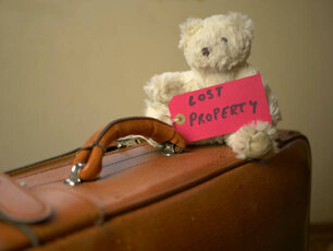 A bear toy on an old suitcase with a "Lost property" label tag