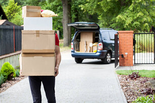 Delivery guy carrying a stack of parcels from his van