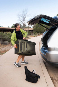 Adult man lifts a suitcase to put in the trunk of a car on a road trip through Arizona, USA