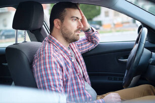 Side view of a young man tired and thinking while sitting in his car