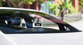 A white car with a black and white Uber beacon in the front windshield