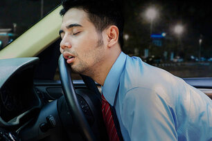 Young businessman looks tired and sleeping inside a car on the steering wheel