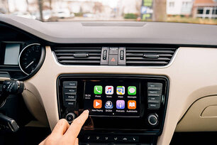 Paris, France - December 13, 2016: Man pressing home button on the Apple CarPlay main screen in modern car dashboard. CarPlay is an Apple standard that enables a car radio or head unit to be a display and controller for an iPhone. It is available on all iPhone 5 and later with at least iOS 7.1.