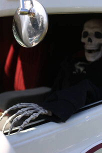 An old vintage car with a plastic skeleton placed inside as a creepy prop.