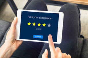 Person using digital tablet computer at home to send customer rating with online website, satisfaction review based on star icons, concept about quality management