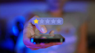 Woman hand showing a mobile phone towards camera viewpoint, digital overlay of rating 1 star
