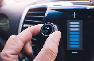 Car owner hand turning volume button of a car audio system in the car