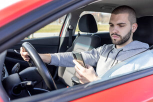 Irresponsible man checking message with smartphone in traffic. Dangerous driving.