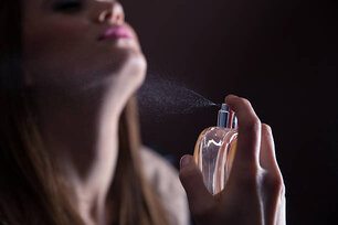 Young woman spraying perfume on her neck